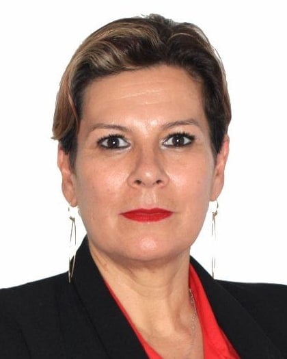 Retrato de Mariela Matthies, con saco negro y blusa roja, de brazos cruzados.